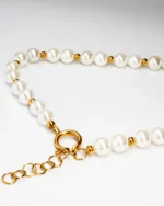 Close-up view of handmade pearl necklace featuring white round pearls with small gold beads, finished with a gold clasp and adjustable chain