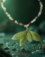 A handcrafted necklace made with colorful mookaite beads featuring a real samara leaf cluster preserved in resin, photographed against a deep green, nature-inspired background.