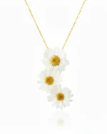 A delicate necklace featuring three real white daisy flowers arranged in a vertical cascade on a fine gold chain, set against a clean white background