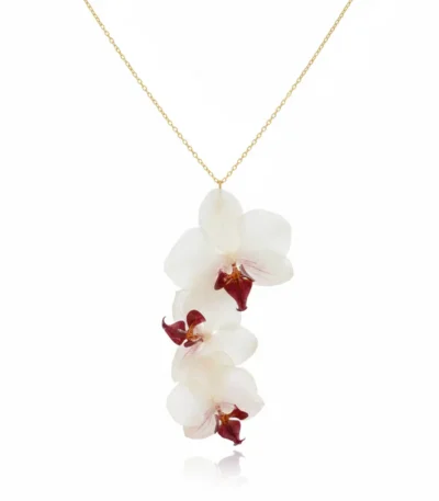 A delicate gold-chain necklace featuring three real white orchid blooms with deep burgundy centers arranged in a vertical cascading design on a white background