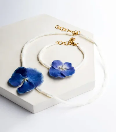 Handmade demi set of necklace and bracelet with real blue hydrangea flowers preserved in UV resin, tubular white shell beads, and gold clasps