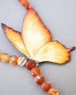 Handmade butterfly necklace with vibrant orange wings and natural carnelian gemstone beads, artistic nature-inspired jewelry design
