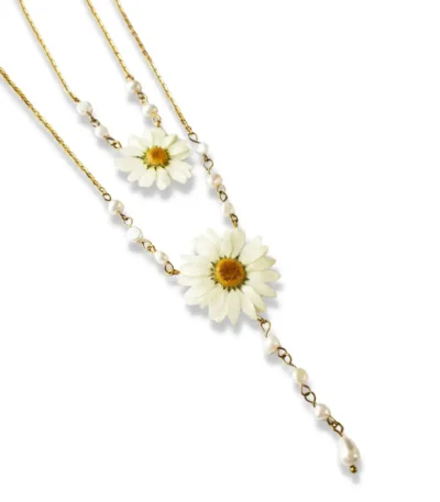 A delicate gold-chain necklace featuring two real pressed daisy flowers, accented with small white pearls and a dangling teardrop pearl, displayed on a white background