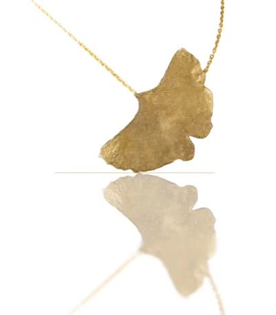 Handmade ginkgo leaf necklace with gold chain, nature-inspired jewelry piece reflecting light on white background
