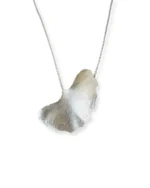 Handmade ginkgo leaf necklace with silver chain, nature-inspired jewelry piece reflected on white surface