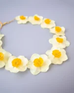 Close-up of handmade choker necklace with real narcissus flowers preserved in UV resin, nature-inspired jewelry on gray background