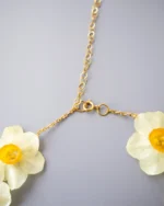 Close-up of handmade narcissus flower choker necklace with gold stainless steel chain and clasp, UV resin preserved natural flowers