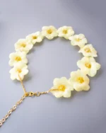 Handmade choker necklace with real narcissus flowers preserved in UV resin, featuring gold stainless steel chain, displayed on gray background