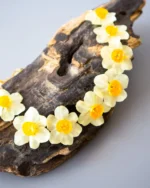 Handmade choker necklace with real narcissus flowers preserved in UV resin, displayed on wooden background, nature-inspired jewelry design