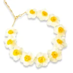 A delicate layered gold necklace featuring two real pressed daisy flowers and small white pearls, displayed on a soft beige fabric with natural light and floral shadows.