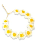 A delicate layered gold necklace featuring two real pressed daisy flowers and small white pearls, displayed on a soft beige fabric with natural light and floral shadows.