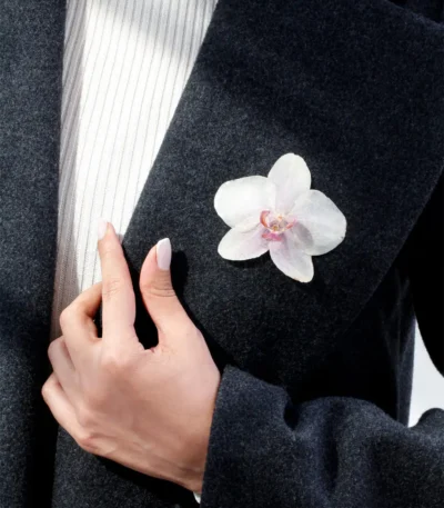 Handmade brooch with a real white orchid flower coated in UV resin, worn on a dark wool coat for an elegant and natural look