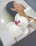 Handmade brooch with a real white orchid flower and purple center, preserved in UV resin, placed on a fashion magazine background