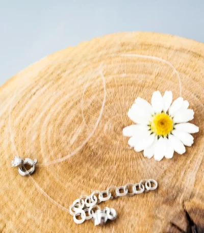 Handmade choker featuring a preserved real daisy flower in UV resin, set on an invisible string with silver clasp and extender chain