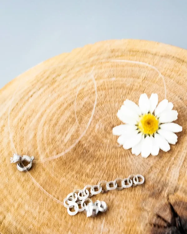 Handmade choker featuring a preserved real daisy flower in UV resin, set on an invisible string with silver clasp and extender chain
