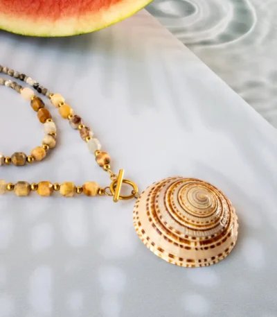 Handmade necklace with natural seashell pendant and gemstone beads, featuring gold stainless steel clasp, displayed on summer background with watermelon