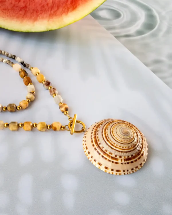 Handmade necklace with natural seashell pendant and gemstone beads, featuring gold stainless steel clasp, displayed on summer background with watermelon