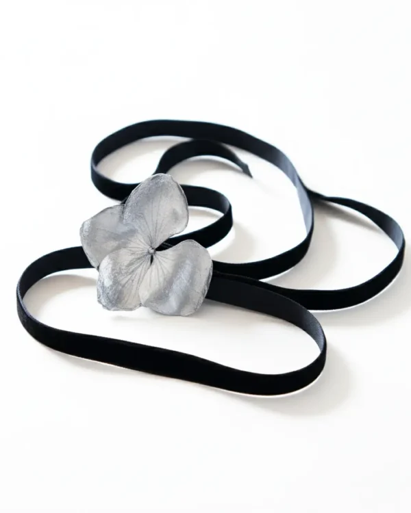 A black velvet choker featuring a silver hydrangea flower centerpiece, displayed on a white background.